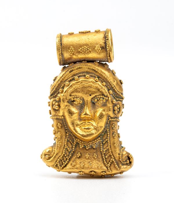 Pendente in oro in stile archeologico raffigurante una maschera 