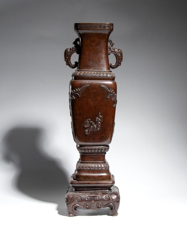 A cast bronze vase with a dark brown patina, a square body, and zoomorphic handles. Meiji period. Japan, second half of the 19th century.