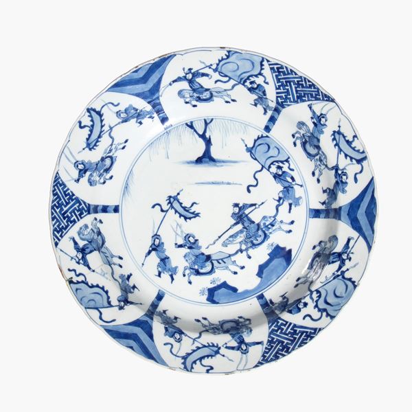 Raro grande piatto in porcellana bianca e blu decorato con scene di battaglia. Cina, dinastia Qing, periodo Kangxi 