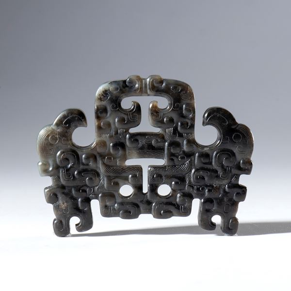 An ornamental pendant in Hotan dark jade, pierced and engraved. China, 18th century.