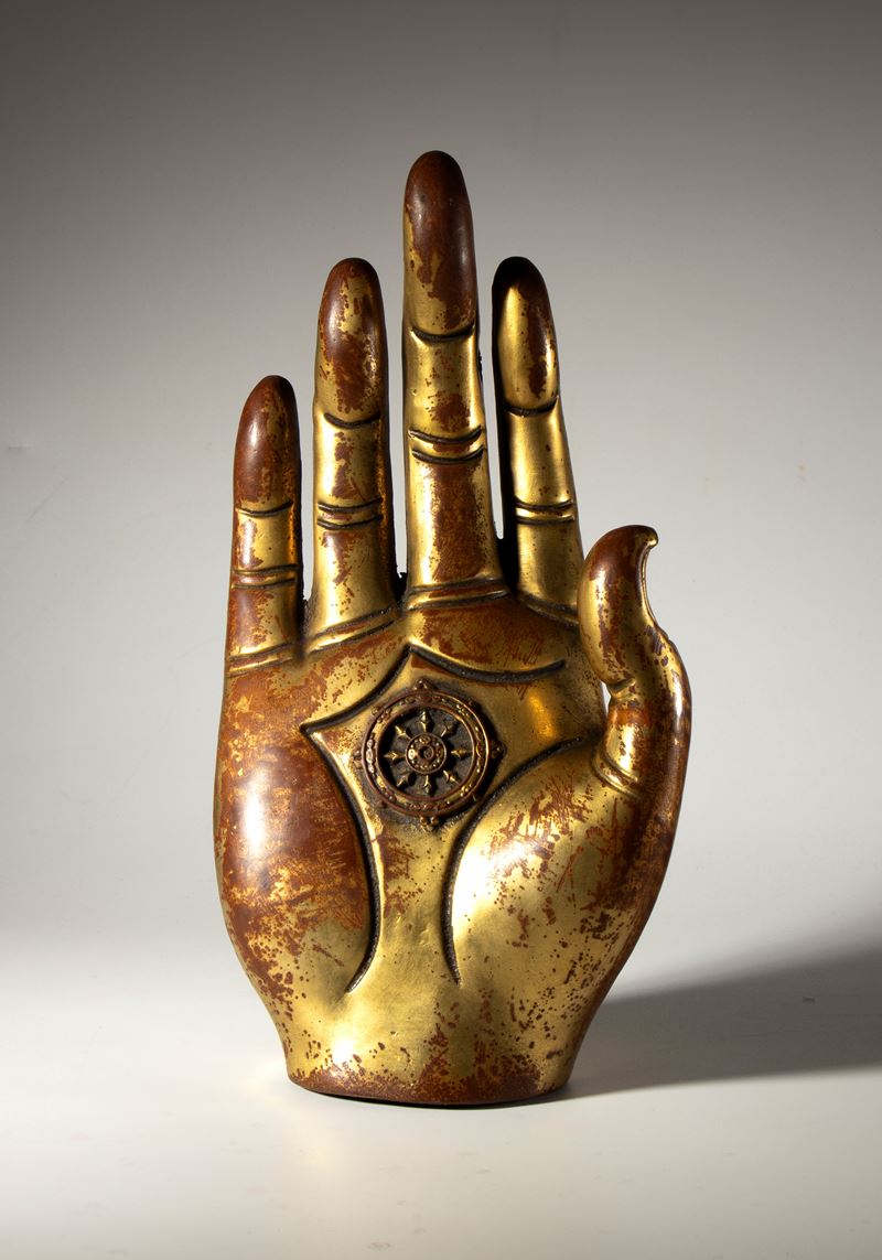 Mano di Buddha in rame parzialmente dorato. Al centro del palmo la ruota del dharma. Birmania, XX...