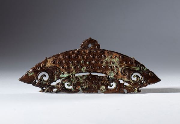 A half-disc ornament. Engraved and perforated Hotan dark jade. Decorated with spiral motifs and a tiger's face. A hole for hanging. China, 17th century.
