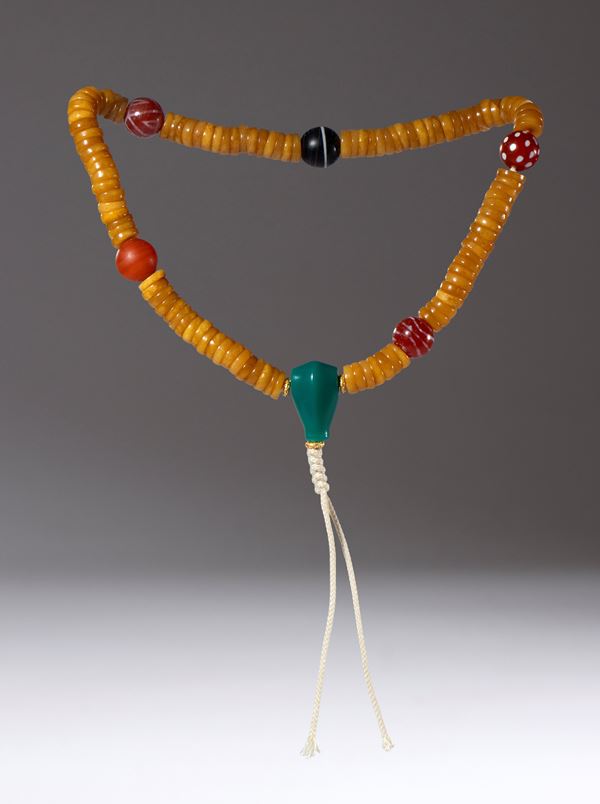 Ritual mala composed of 108 disc-shaped bone beads interspersed with five agate, carnelian, and glass beads with a central green jade bead. China, Qing Dynasty (1644-1911), 19th century