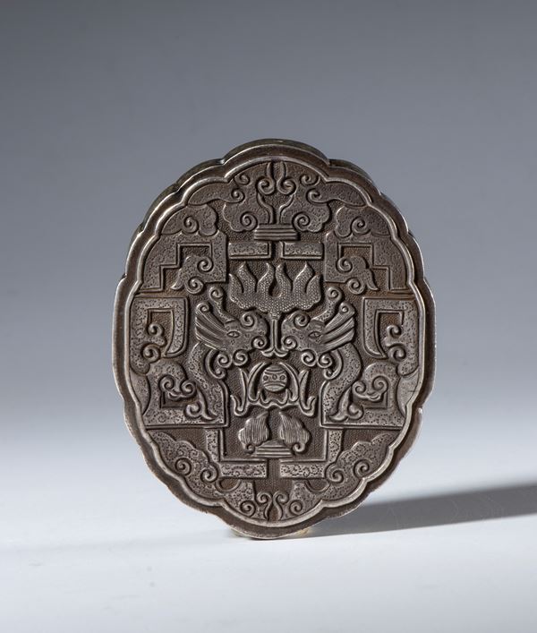 A decorative element in embossed and engraved silver with a through-hole for hanging. Richly decorated with schematic dragons and clouds. China, 19th century.
