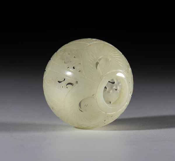 A Hotan jade bead decorated with an intricate engraved and traforated leaves motif. The bead is carved from a hollow jade sphere. China, 19th century.