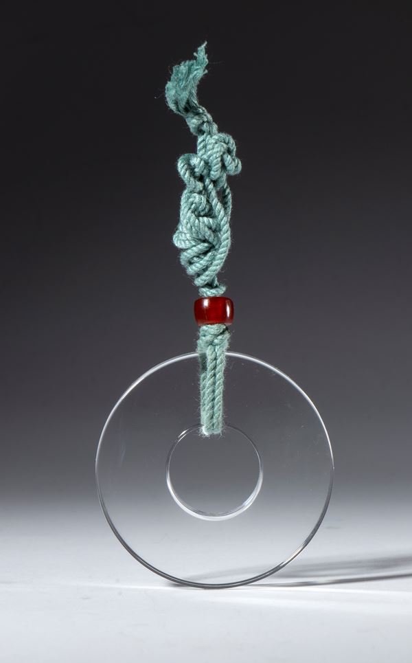 Ornamental glass disc with a cotton cord and carnelian clasp. China, 19th century.