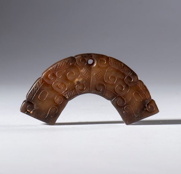 A Hotan jade half-disc ornament engraved with cloud motifs and a hanging hole. China, Qing Dynasty (1644–1911), 19th century.