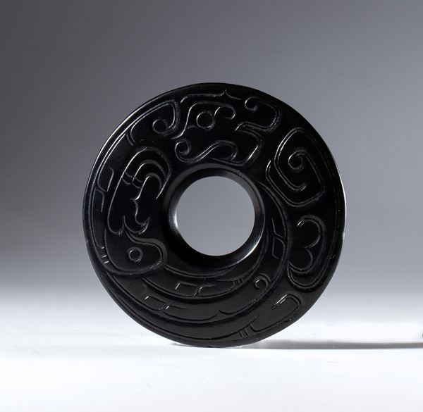 A BI disk in Hotan black jade with an engraved decoration depicting a schematic dragon. China, 19th century.