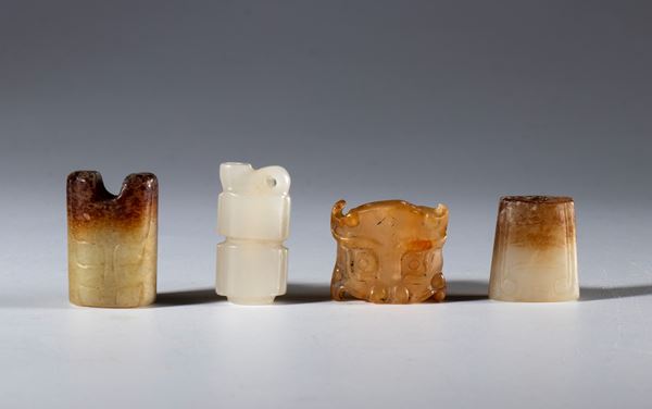 A lot of four necklace elements carved and engraved in Hotan jade. Three depict schematic tiger heads. China, Qing Dynasty (1644–1912), 16th century.