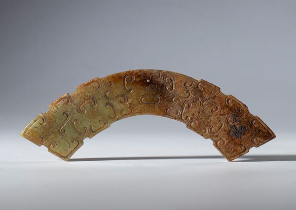 A Hotan jade half-disc ornament decorated with a cloud motif and a central hole for suspension. China, Qing Dynasty (1644–1912), 19th century.