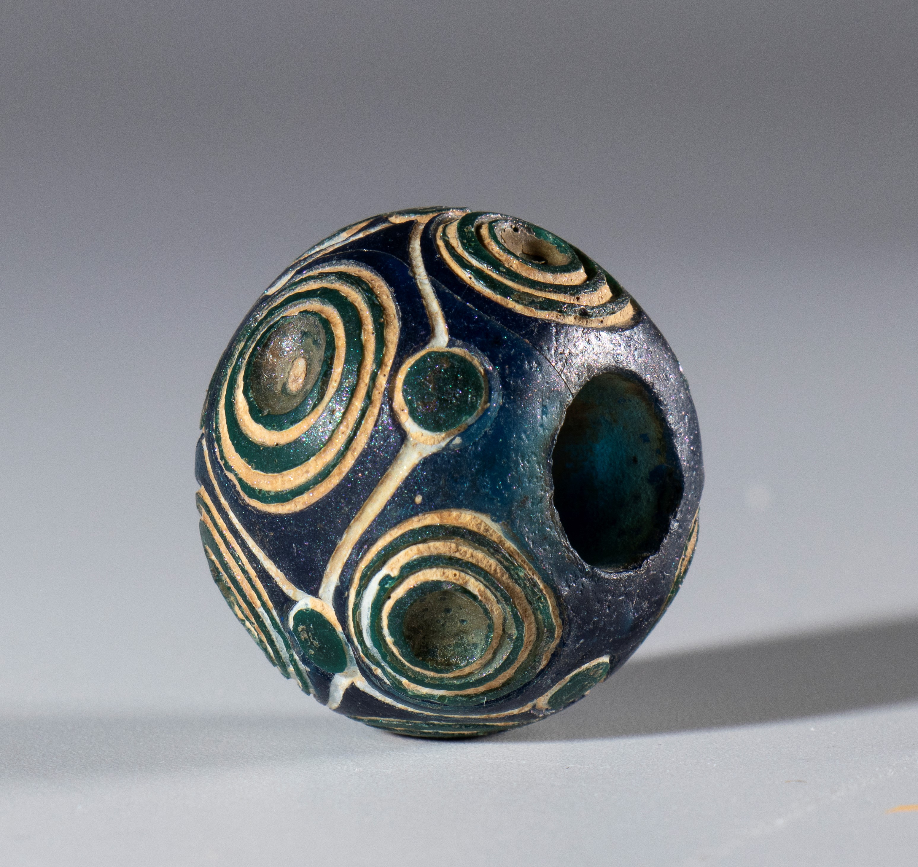 Perla antica, vetro opaco bianco con inserti blu scuro a motivi a spirale (Cina, Periodo degli St...