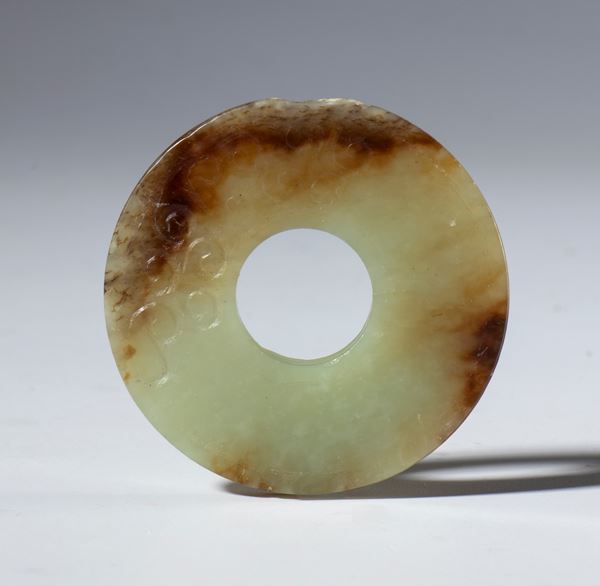 A beautiful Bi disk in transparent jade with dark hues and small spiral carvings. China, Qing Dynasty (1644-1912), late 19th century.