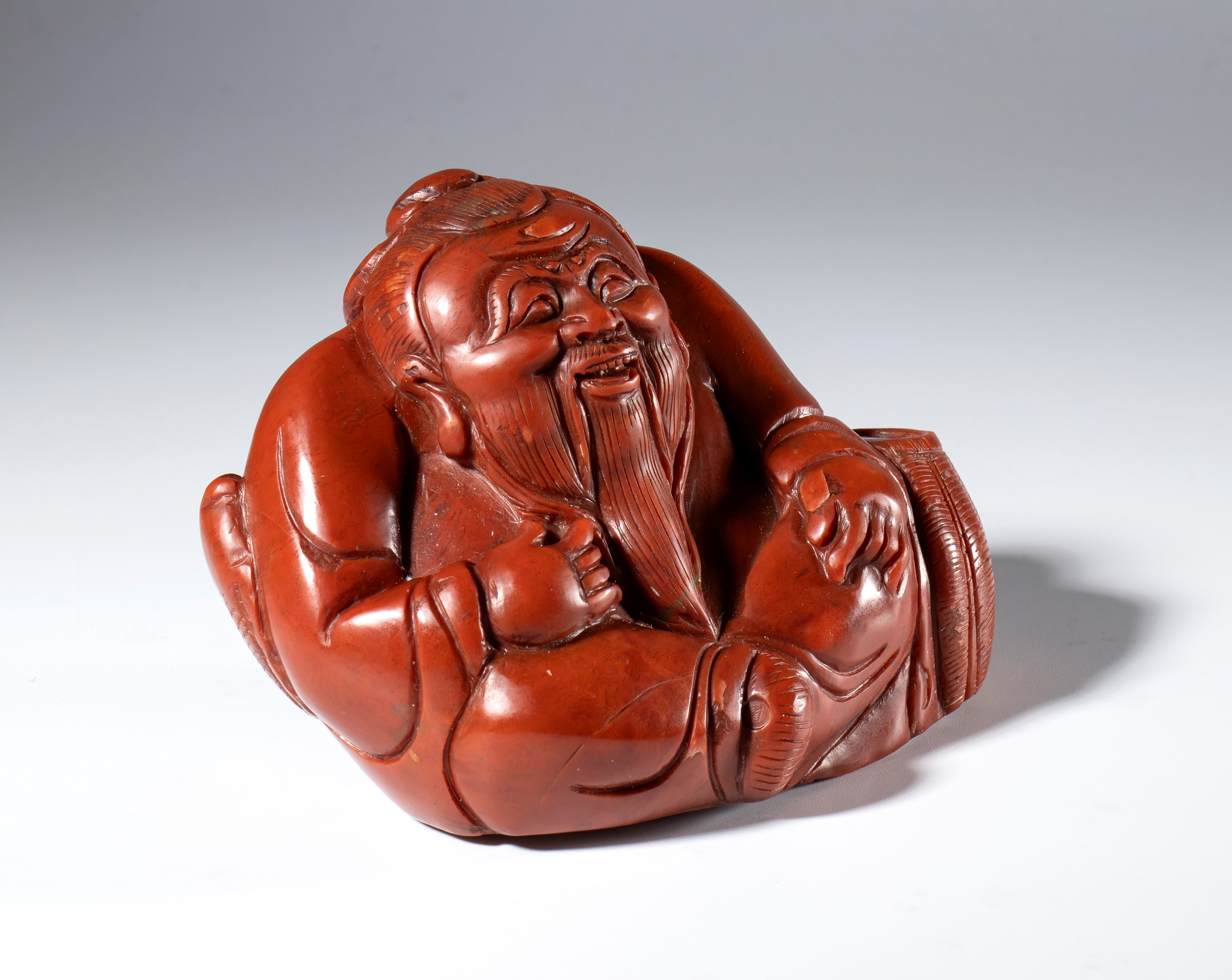 Figura di saggio scolpita e incisa in pietra saponaria rosso corallo. Cina, inizio XX secolo