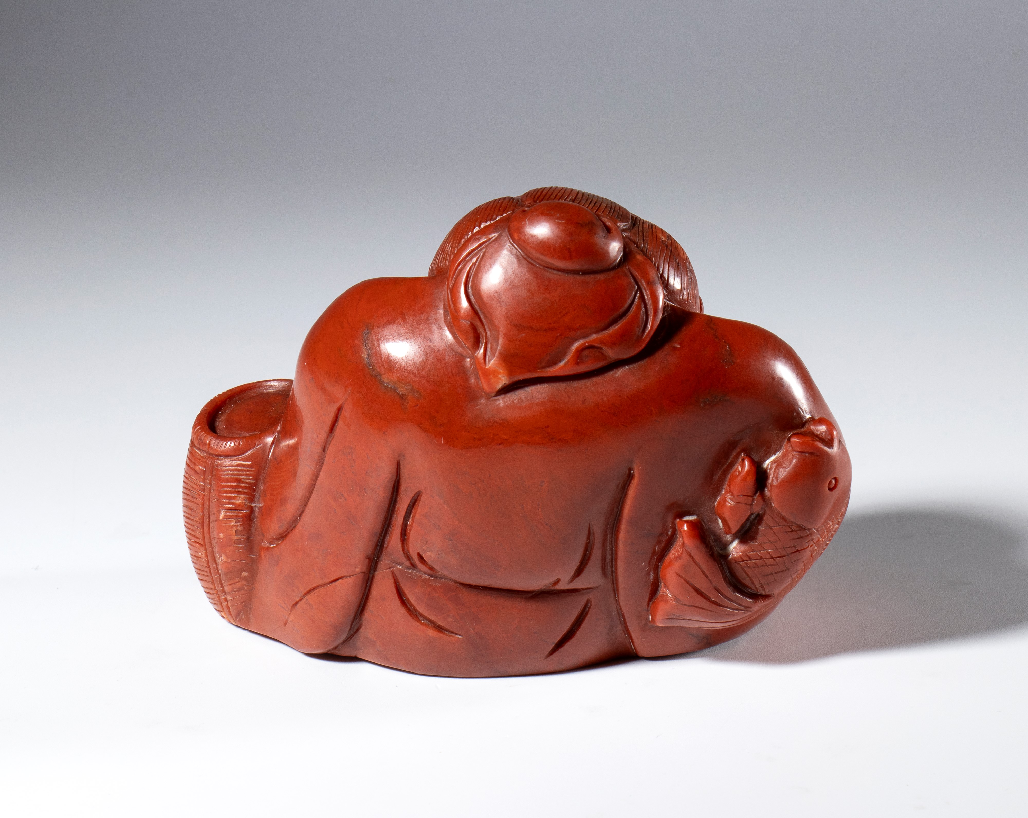 Figura di saggio scolpita e incisa in pietra saponaria rosso corallo. Cina, inizio XX secolo