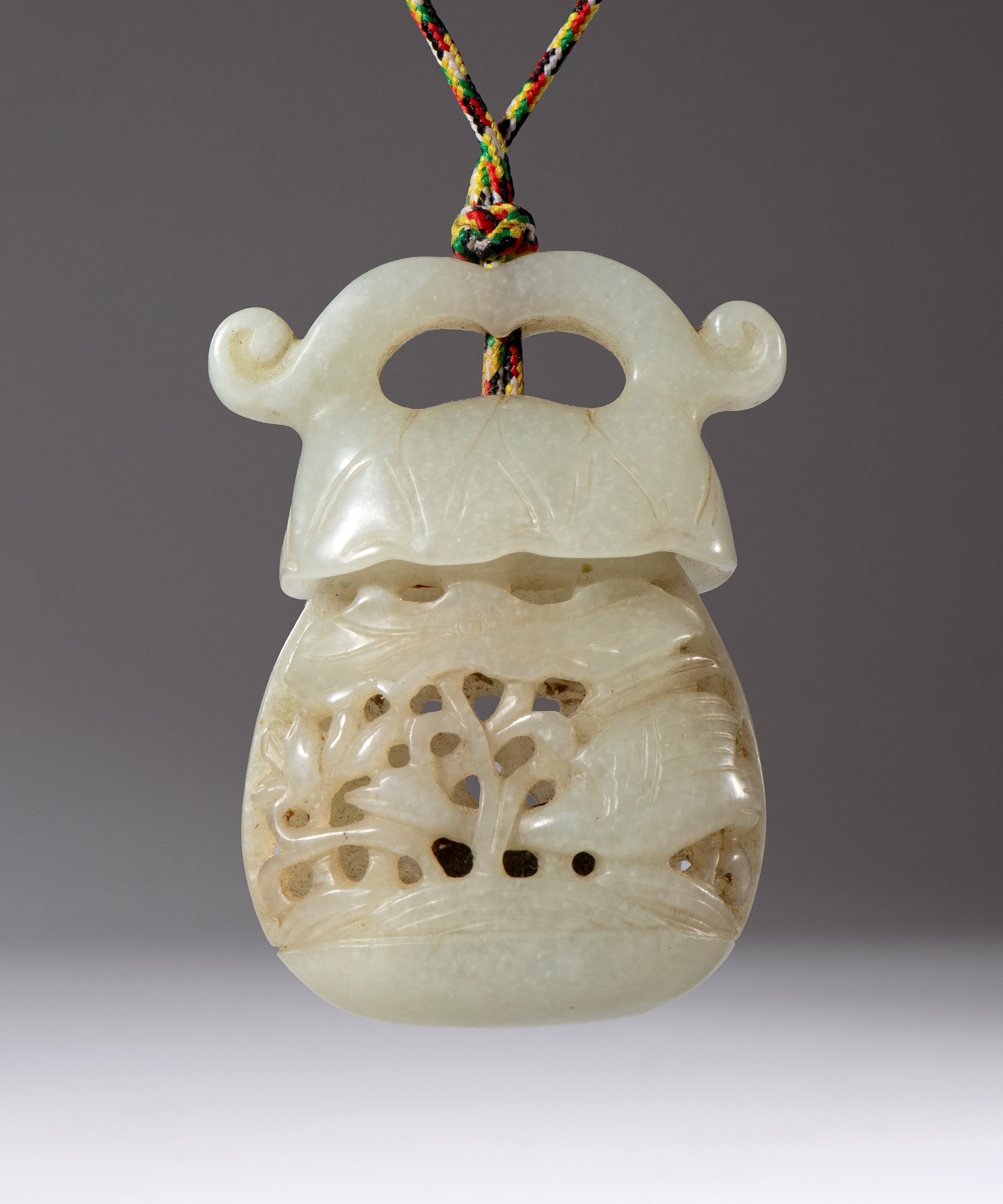 Ciondolo contenitore in giada scolpita e traforata, con inserto di legno di sandalo, Cina (dinast...