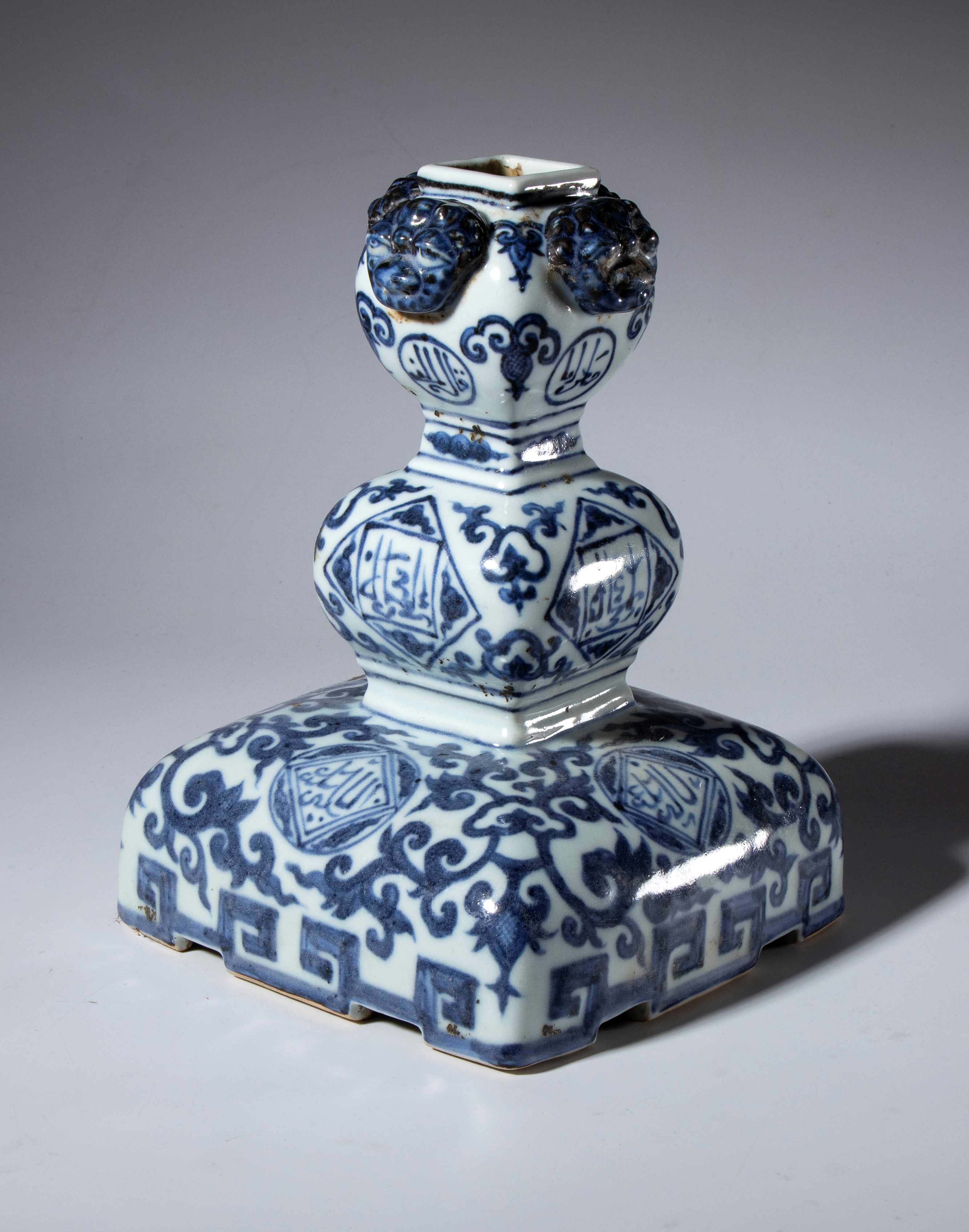 Candeliere in porcellana bianca e blu con decori schematizzati e medaglioni con iscrizioni in ara...