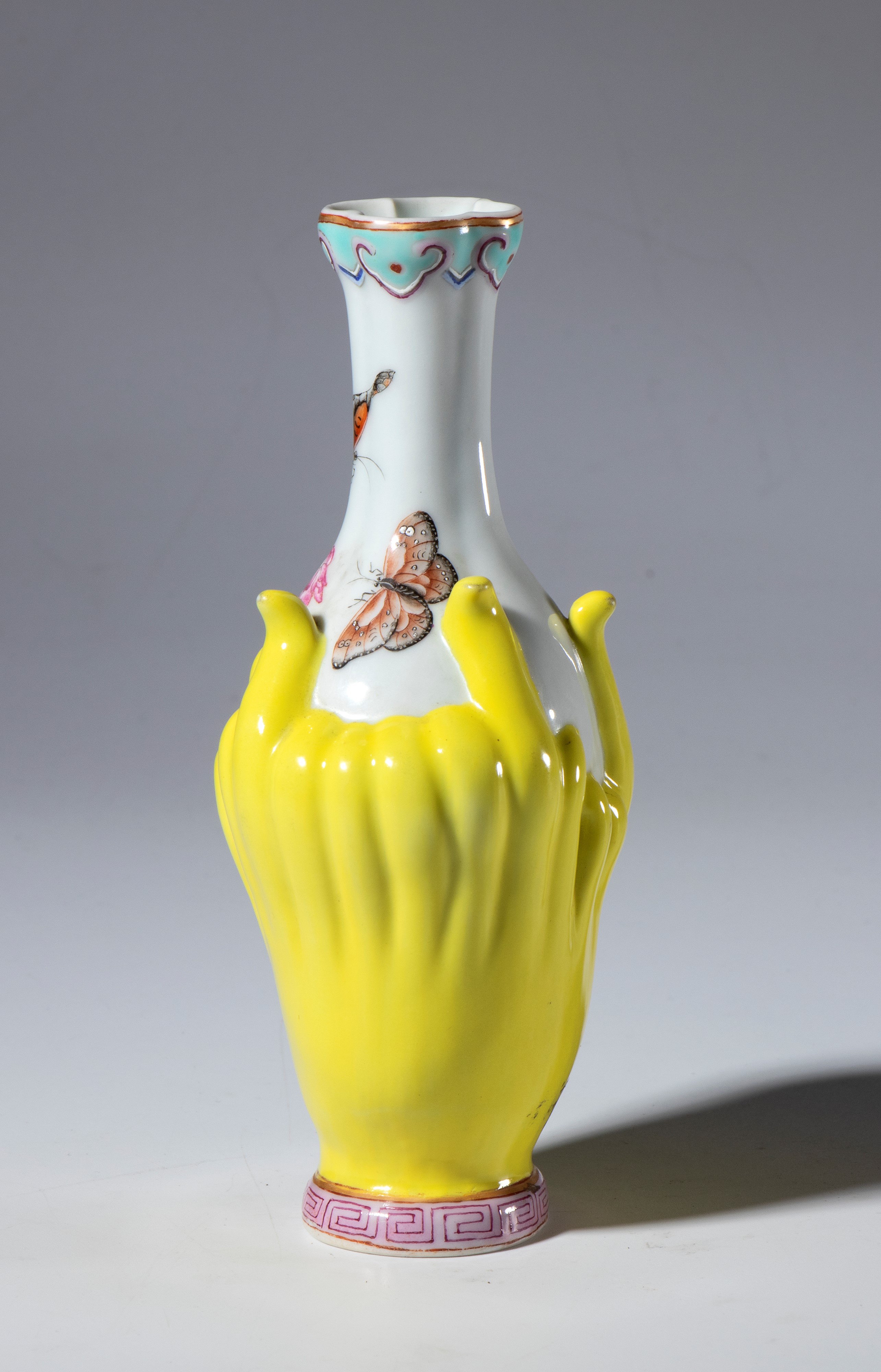 Vasetto in porcellana dipinto con fiori e farfalle. Il corpo del vaso ricorda il frutto dell'albe...