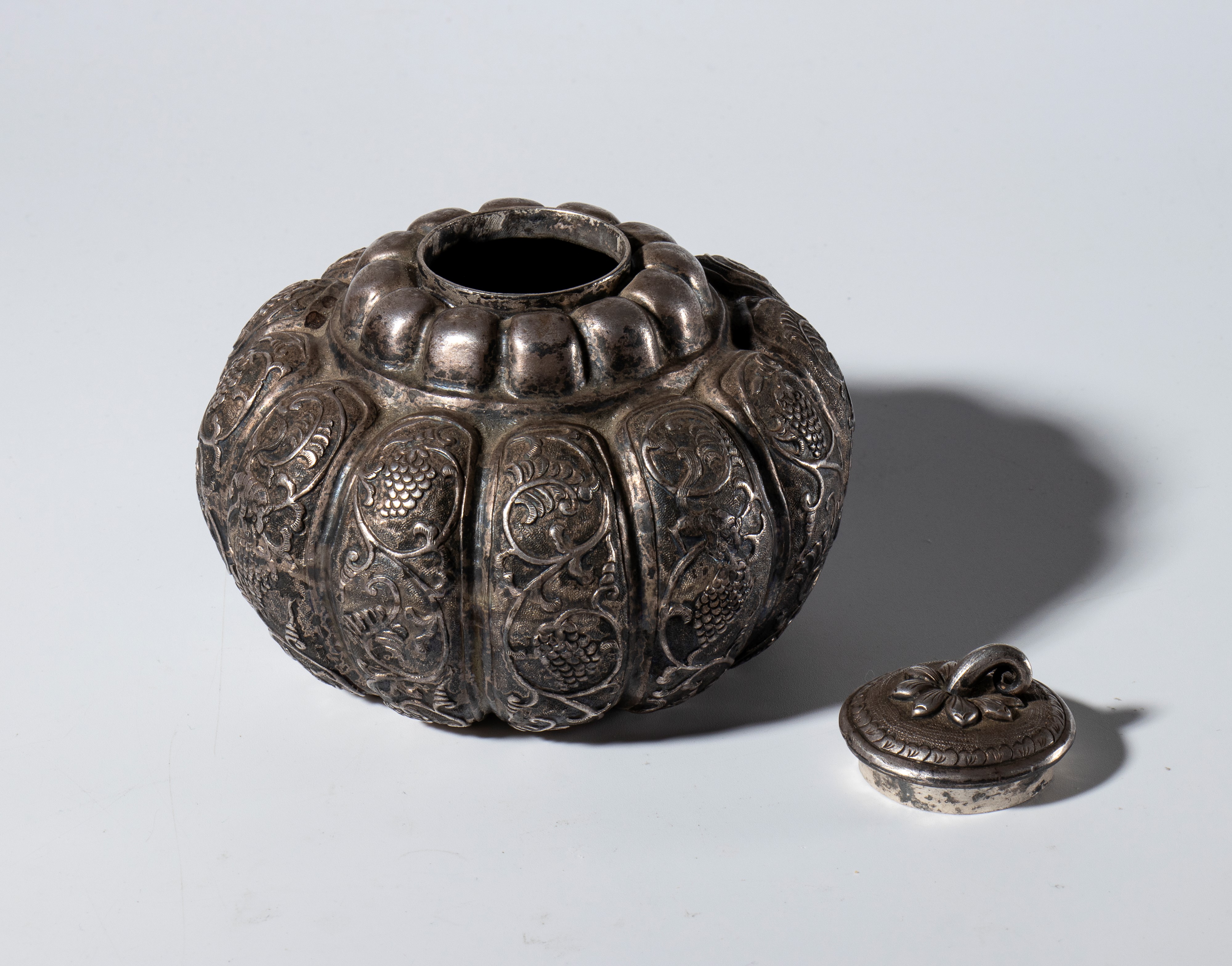 Contenitore con coperchio a forma di zucca, metallo argentato, incisioni a tralci vegetali e figu...
