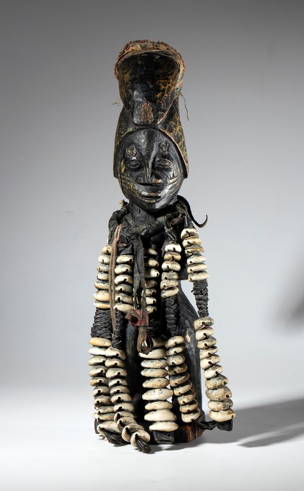 A fetish made of wood, cloth, and cowrie shells, depicting Eshu Elegba, a Yoruba deity. Africa, Nigeria, ca. 1900.