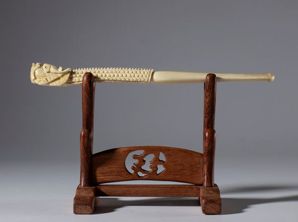 A carved elephant ivory pipe in the shape of a dragon's head on a wooden base. China, 19th century.