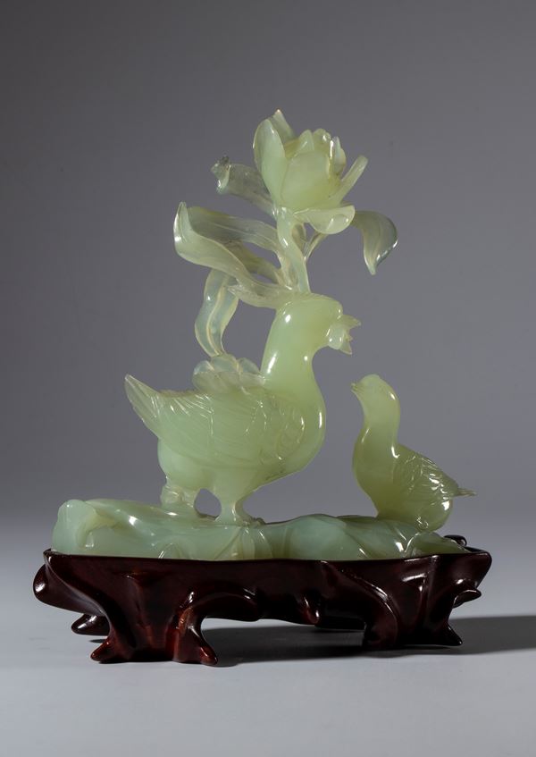 Green jade sculpture on a wooden base depicting a pair of birds and a large flower. China, 20th century.