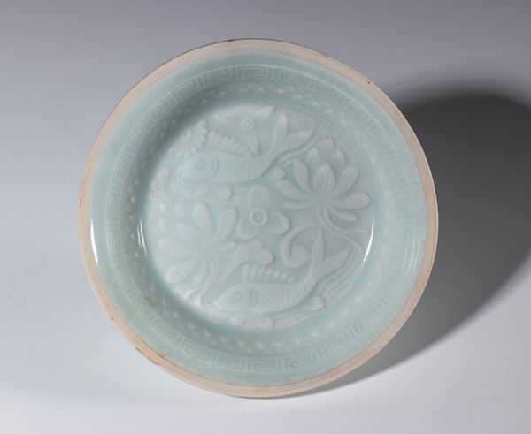 A small celadon-glazed porcelain bowl. A pair of fish and leaves adorn the bottom. China, early 20th century.