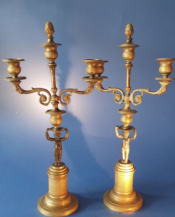 Pair of candlesticks with cherubs. Gilded bronze with black patination. Early 19th century.