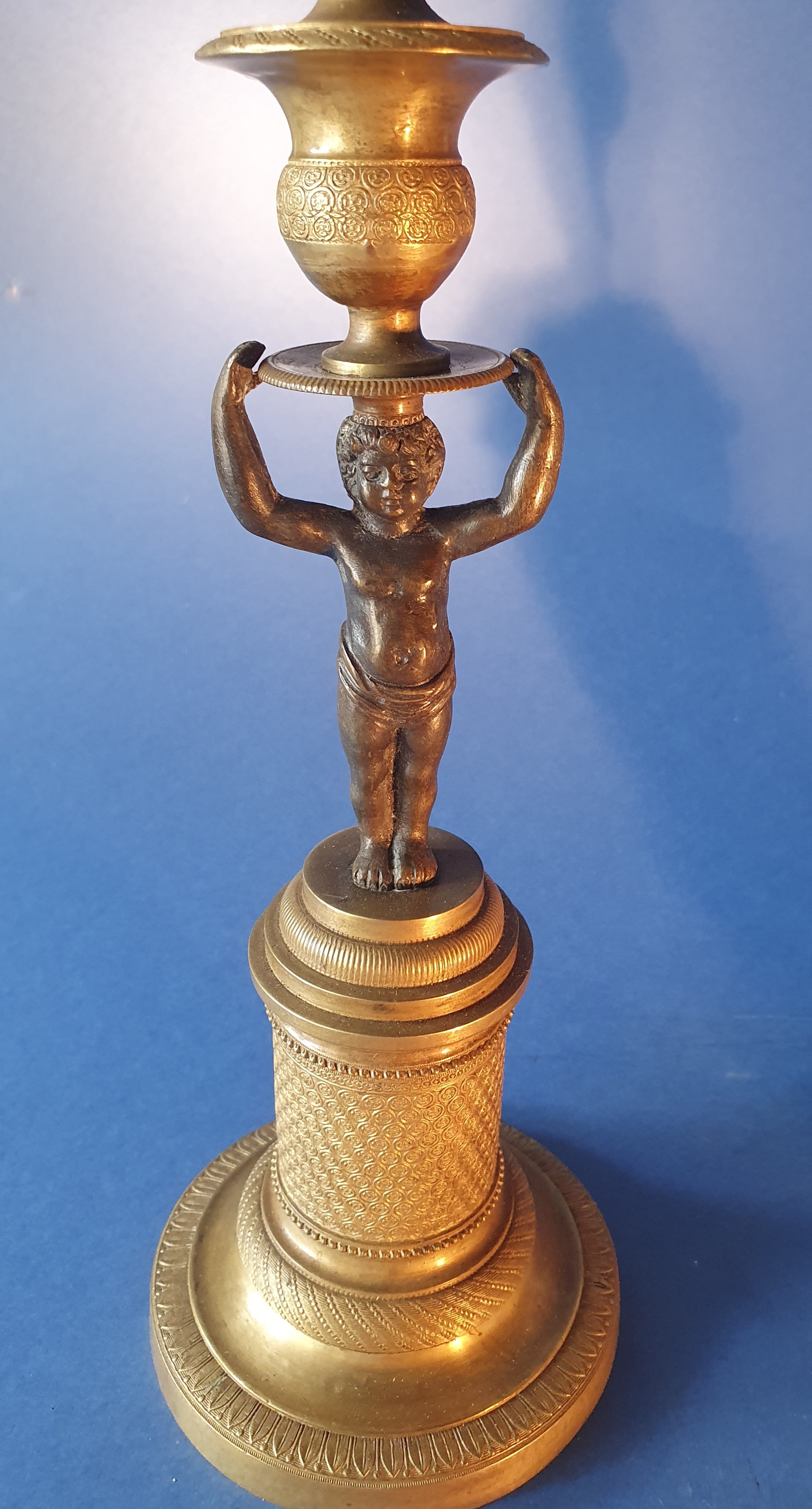 Coppia di candelieri con putti. Bronzo dorato e patinato nero. Primo XIX secolo.
