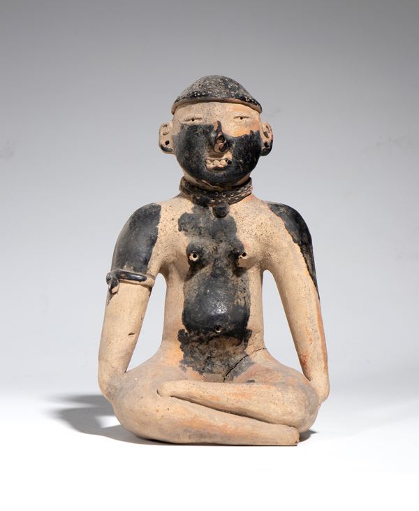 Pre-Columbian seated terracotta figure with black pigments on the face and torso. Mexico, Classic Period.