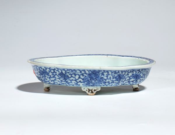 A blue and white porcelain bowl with feet decorated with an ornamental motif of vegetal scrolls. China, 20th century.