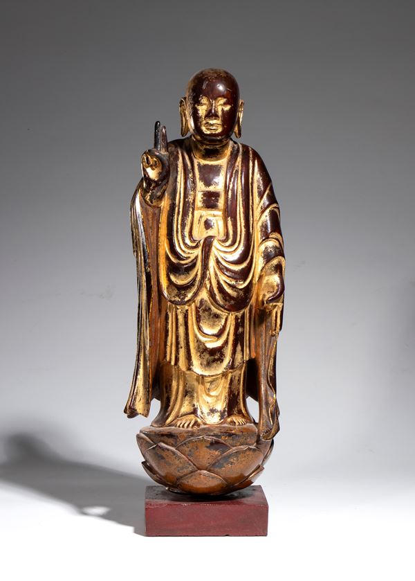 Gilded wooden figure depicting a Buddhist monk (Arhat/Luohan) standing on a lotus. China, late Ming Dynasty, 17th century.