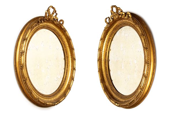 Pair of carved and gilded oval mirrors