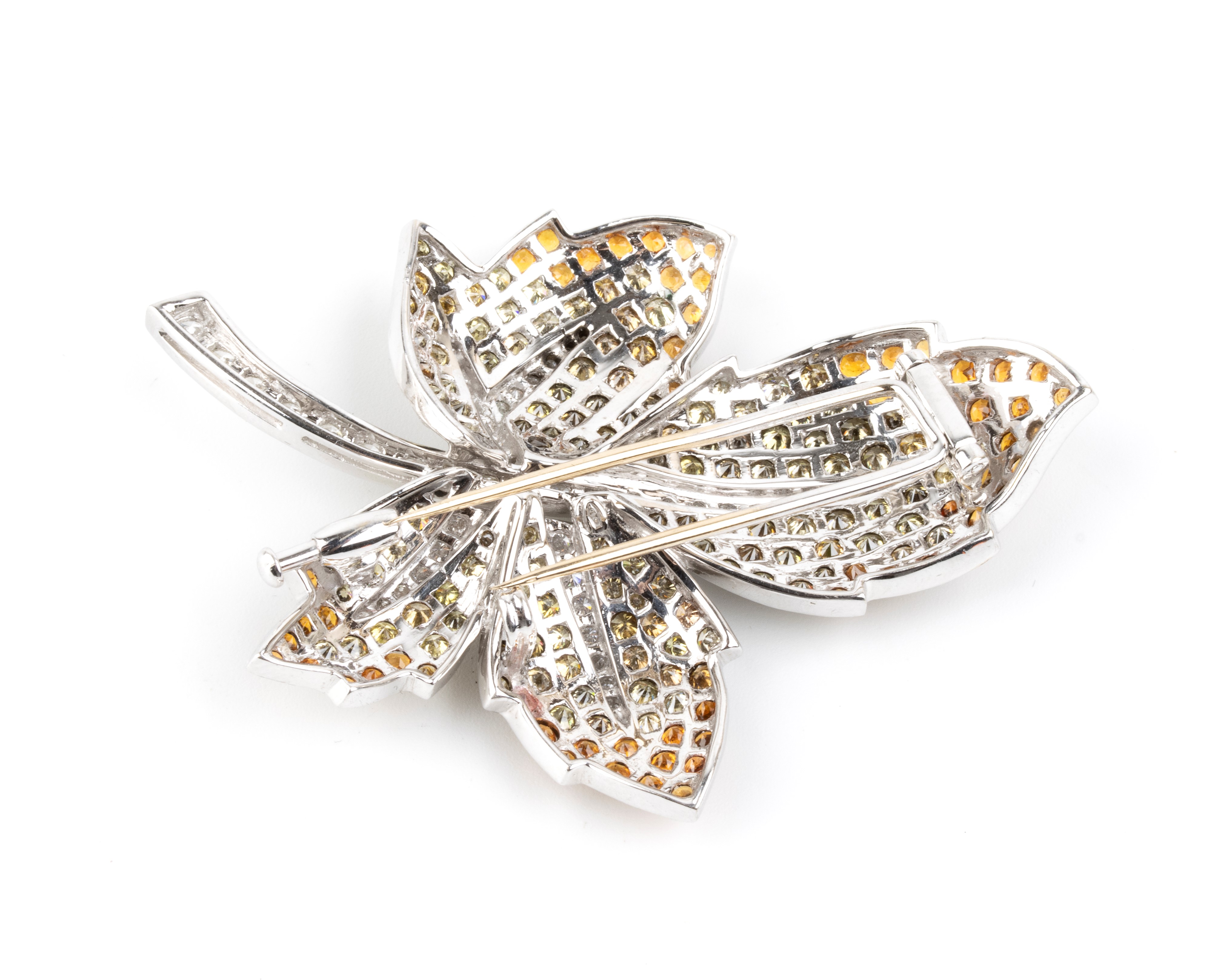 Spilla in oro bianco 18k, modello foglia con pavé di diamanti e corindoni arancio