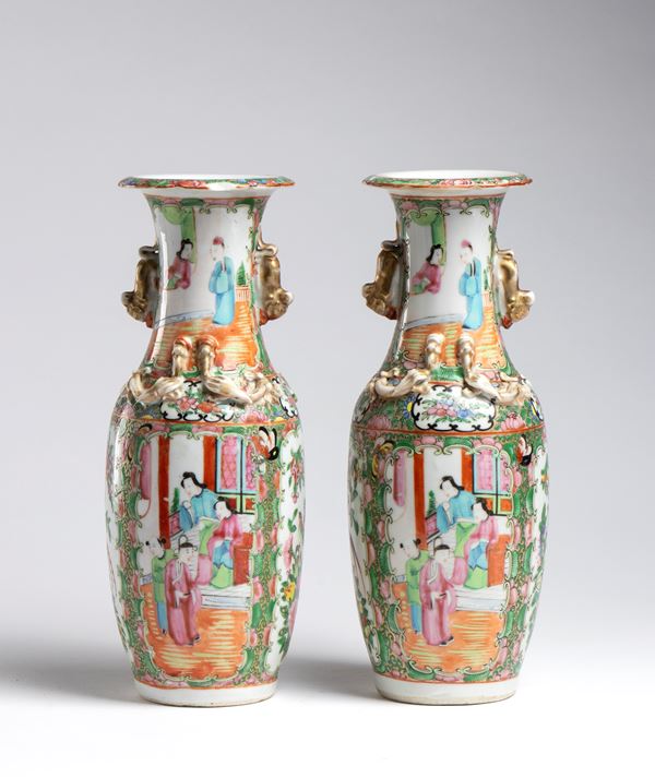 A pair of richly decorated Canton baluster vases in the Famille Rose style with scenes of courtly life, flowers, and birds, with side handles in the shape of chilong dragons. China, early 20th century.