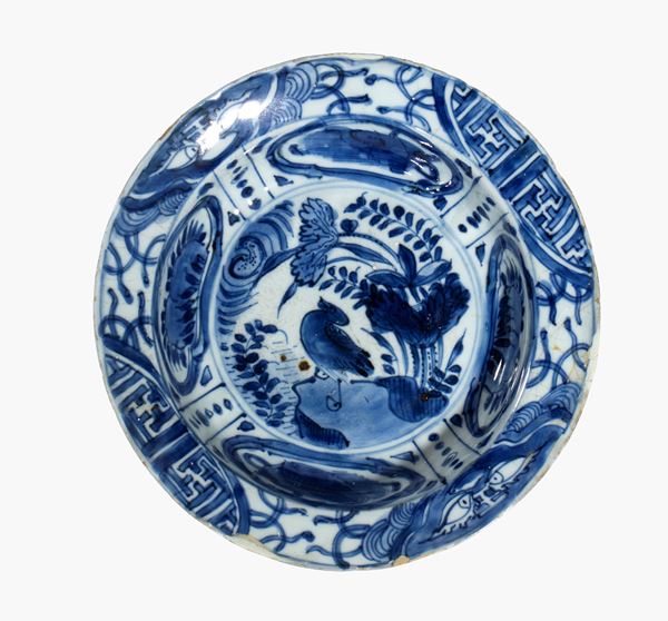 A blue and white Kraak porcelain plate decorated with a floral motif and birds in the center, with a paneled rim. China, Ming Dynasty, late 17th century.