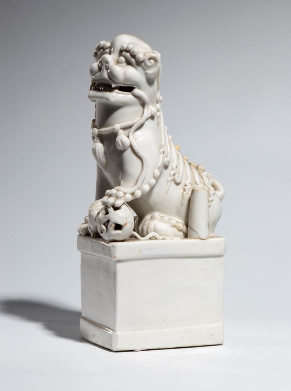 A Dehua "blanc de Chine" porcelain Foo dog depicted with its paw on a sphere. Qing Dynasty, late 18th-19th century.