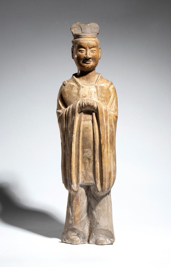 Figura in ceramica raffigurante un funzionario di corte, stante con le mani raccolte nelle ampie maniche e copricapo da ufficiale. Cina, dinastia Tang, VIII secolo