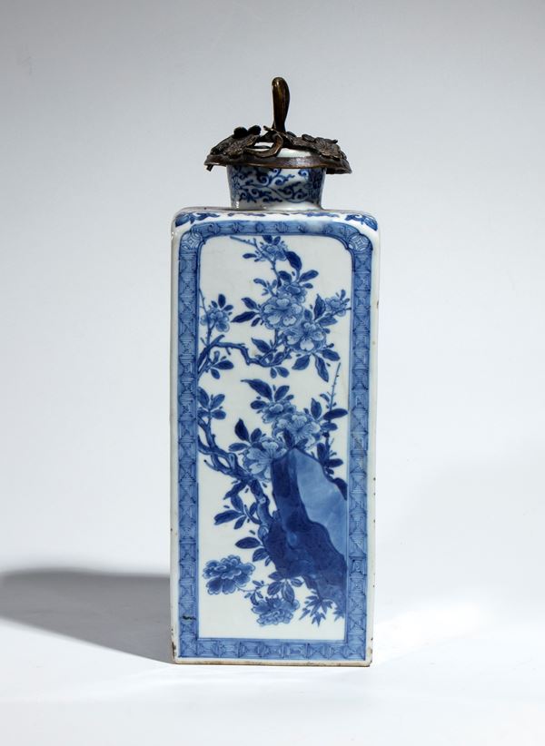 Bottiglia quadrata in porcellana  bianca e blu decorata con motivi floreali che rappresentano le stagioni (pruno, peonia, loto e crisantemo) con un tappo in bronzo traforato. Cina, dinastia Qing, periodo Kangxi 